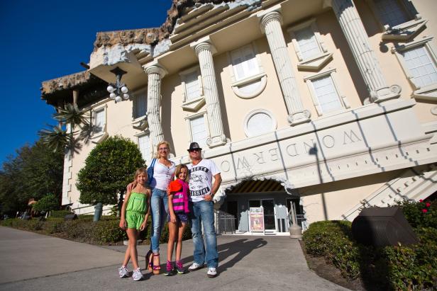 Eine Familie posiert vor dem auf dem Kopf stehenden WonderWorks-Gebäude.