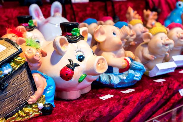 Eine Reihe von bemalten Sparschweinen und Hasenfiguren stehen auf einem roten Tuch.