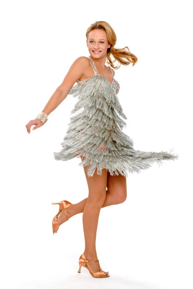 Eine Frau in einem silbernen Fransenkleid tanzt auf einer Bühne.