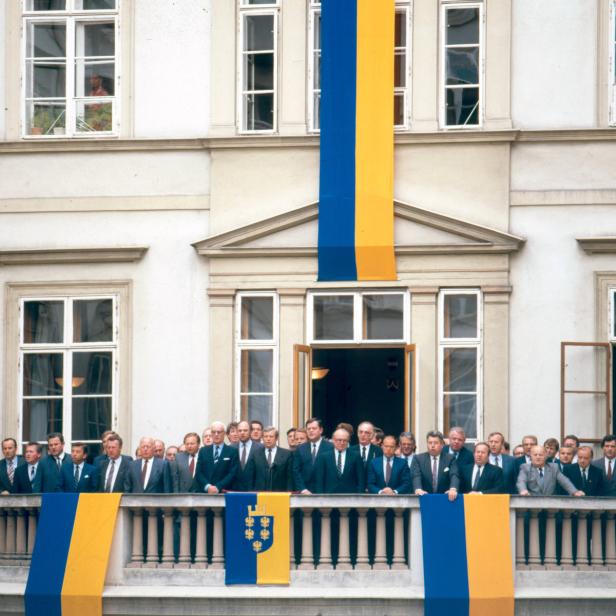 Eine Gruppe von Männern auf einem Balkon, geschmückt mit blau-gelben Flaggen.