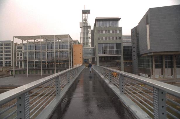 Eine Person geht über eine Brücke in einem modernen Stadtteil.