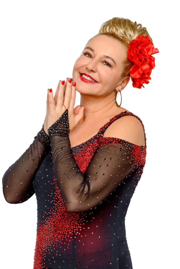 Eine lächelnde Frau mit roter Blume im Haar und einem rot-schwarzen Kleid.
