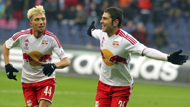 Zwei Fußballspieler von Red Bull jubeln auf dem Spielfeld.