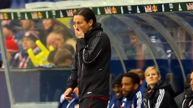 Ein Trainer steht an der Seitenlinie und blickt besorgt auf das Spielfeld.