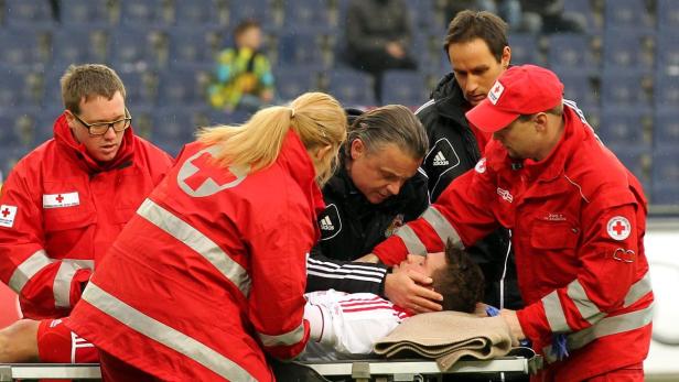 Ein verletzter Fußballspieler wird von Sanitätern auf einer Trage vom Spielfeld gebracht.