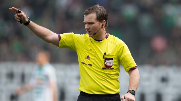 Ein Fußballschiedsrichter zeigt mit erhobenem Arm eine Entscheidung an.