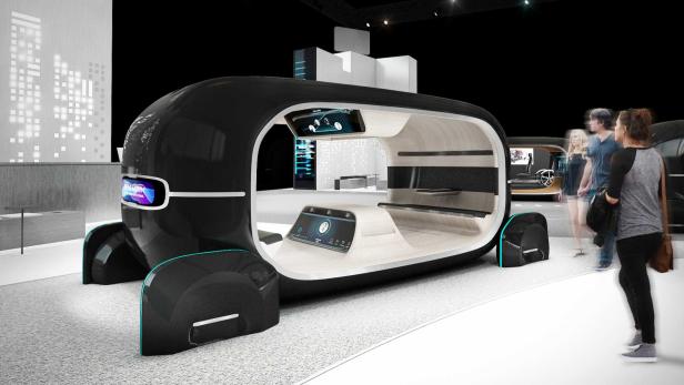 Ein futuristisches, autonomes Fahrzeug mit offenem Innenraum wird auf einer Ausstellung gezeigt.