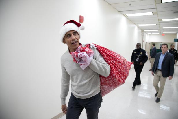 Barack Obama trägt einen Weihnachtsmannhut und einen Sack voller Geschenke.
