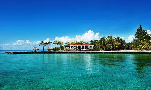 Ein tropisches Resort mit Palmen und türkisfarbenem Wasser unter blauem Himmel.