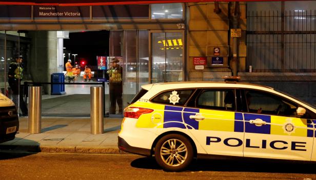 Police officers stand at the end of a tram platform following a stabbing at Victoria Station in Manchester