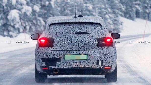 Ein getarntes Auto fährt auf einer verschneiten Straße.