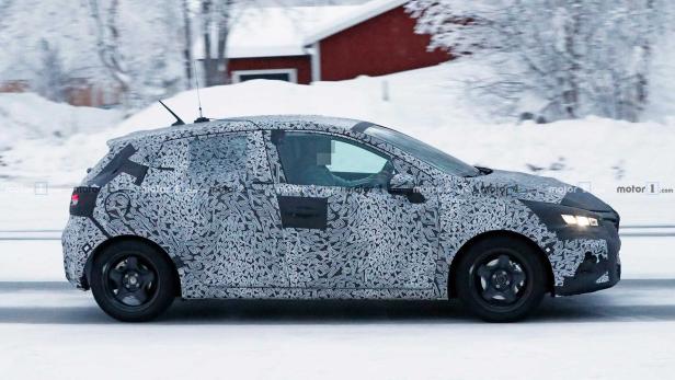 Ein mit Tarnmuster beklebtes Auto fährt auf einer schneebedeckten Straße.