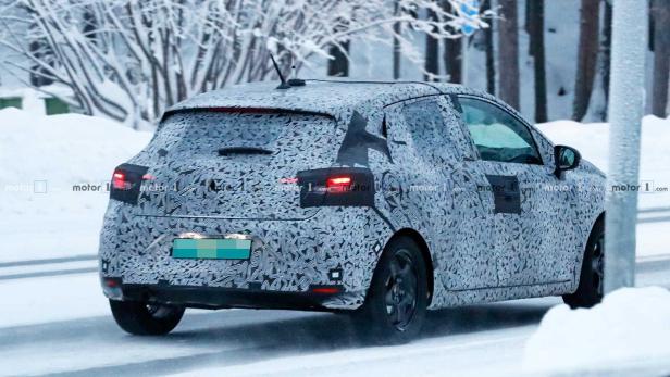 Ein mit Tarnmuster beklebtes Auto fährt auf einer verschneiten Straße.