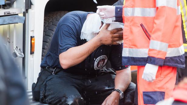 Ein erschöpfter Feuerwehrmann wird von einem Sanitäter versorgt.