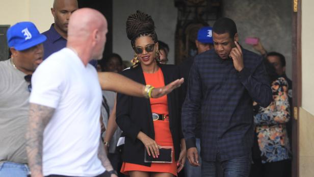 Beyoncé und Jay-Z verlassen ein Gebäude, begleitet von Sicherheitsleuten.