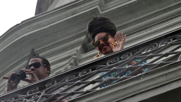 Rihanna und Jay-Z winken von einem Balkon.