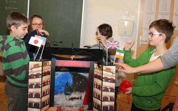 Kinder spielen mit einem Puppentheater, das mit Flaggen von Japan, den USA, Großbritannien und Indien geschmückt ist.