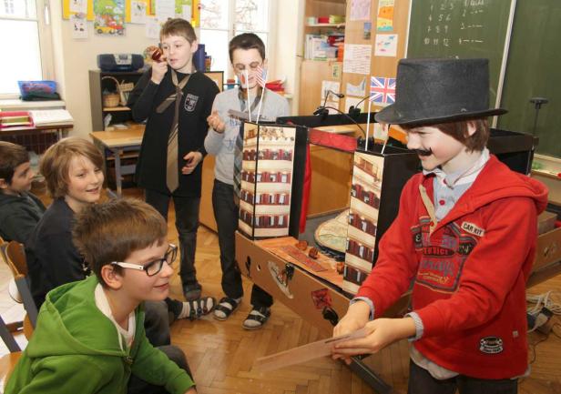 Eine Gruppe von Jungen spielt mit einem selbstgebauten Theater mit Union-Jack-Flaggen.