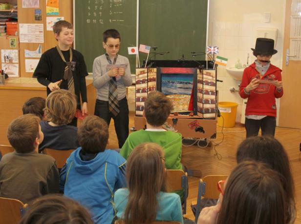 Schüler führen ein Puppentheaterstück vor Publikum auf.