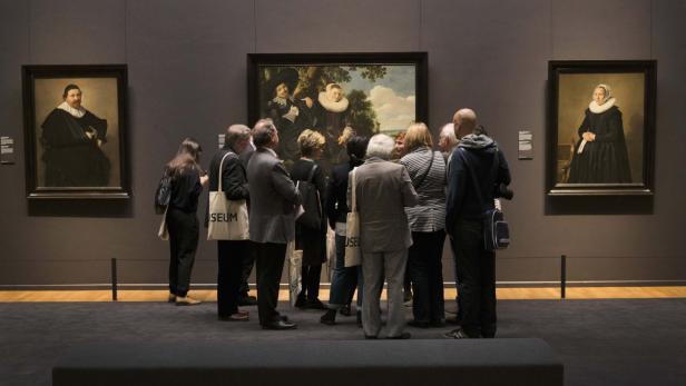 Eine Gruppe von Menschen betrachtet Gemälde in einem Museum.