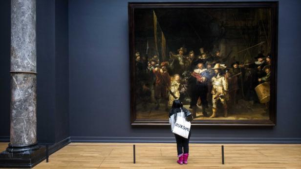 Eine Besucherin betrachtet Rembrandts „Die Nachtwache“ im Rijksmuseum.