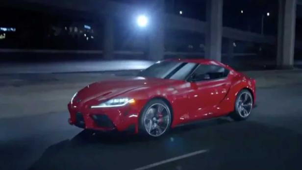Ein roter Toyota Supra fährt nachts auf einer Straße.