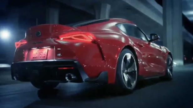 Ein roter Toyota Supra fährt auf einer dunklen Straße.