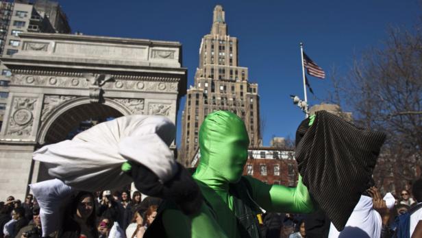 Eine Person in einem grünen Ganzkörperanzug nimmt an einer Kissenschlacht im Washington Square Park teil.