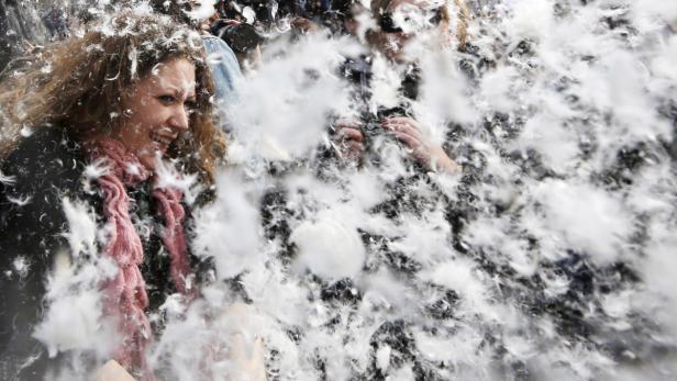 Eine Frau lacht inmitten einer Wolke aus weißen Federn.