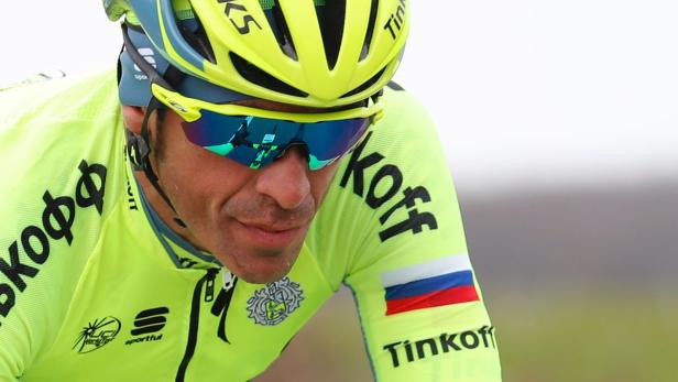 Ein Radrennfahrer in gelber Sportbekleidung und Helm mit verspiegelter Sonnenbrille.