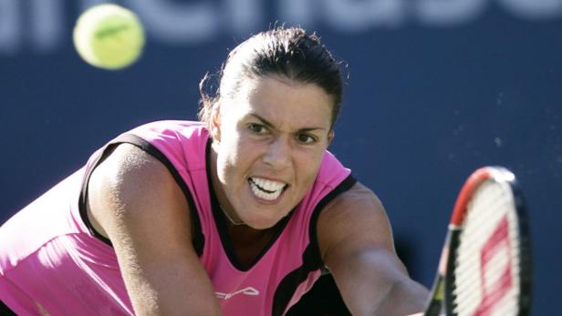 Eine Tennisspielerin schlägt einen Ball mit ihrem Schläger.