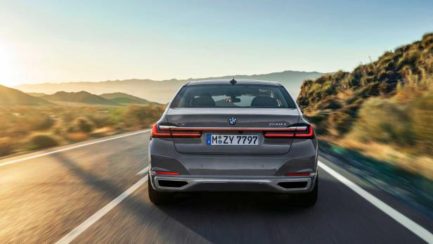 Die Rückansicht eines grauen BMW 750Li auf einer Landstraße.