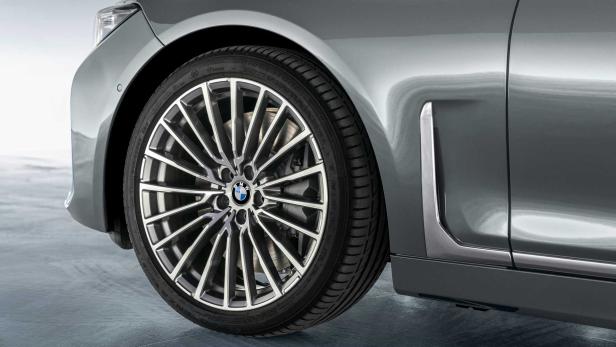 Nahaufnahme des Rads eines grauen BMW mit filigranen Speichenfelgen.