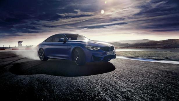 Ein blauer BMW M4 driftet auf einer Rennstrecke.