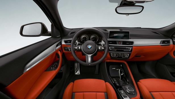 Innenraum eines BMW mit orangefarbenen Ledersitzen.