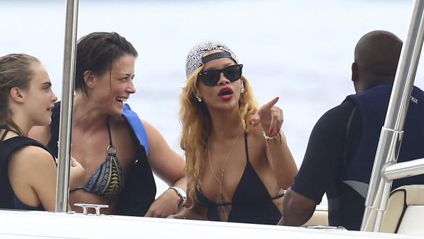Rihanna und andere Personen auf einem Boot, sie zeigt mit dem Finger auf etwas.