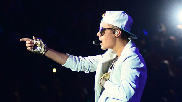 Justin Bieber tritt in einem weißen Anzug und einem goldenen Handschuh auf der Bühne auf.
