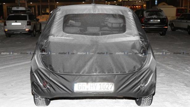 Ein mit einer Plane abgedecktes Auto steht auf einer verschneiten Straße.