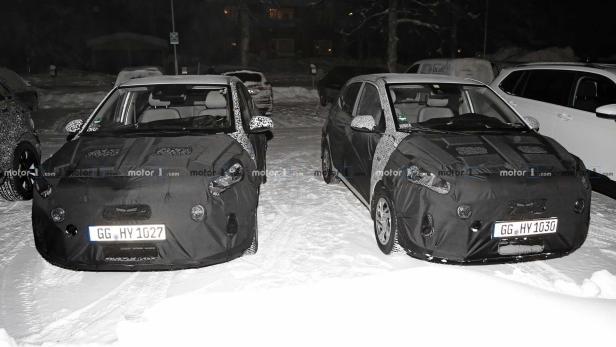 Zwei Prototypen von Autos stehen im Schnee, teilweise mit Tarnfolie bedeckt.