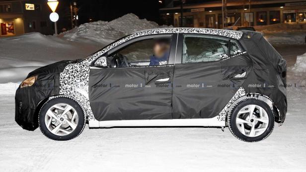 Ein getarntes Auto fährt auf einer schneebedeckten Straße.