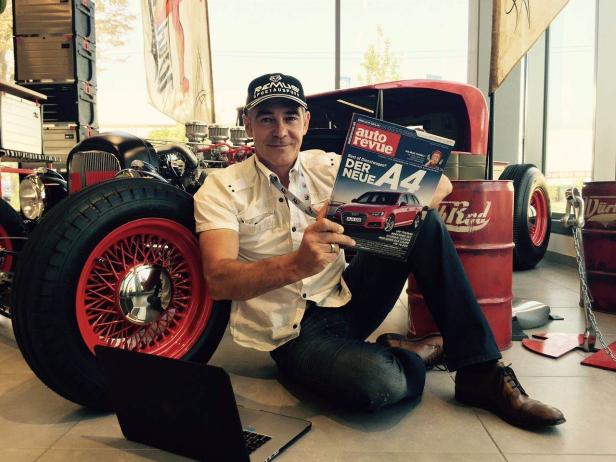Ein Mann sitzt vor einem Hot Rod und liest die „Auto Revue“ mit dem neuen A4 auf dem Cover.