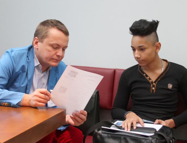 Zwei Männer sitzen an einem Tisch, einer liest ein Dokument.