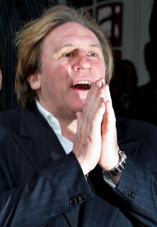 Gérard Depardieu mit gefalteten Händen in einem dunklen Anzug.
