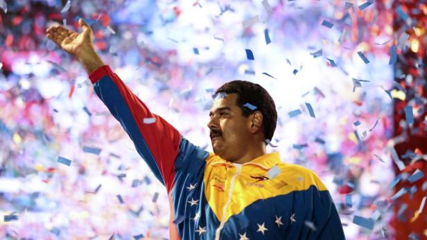 Nicolás Maduro feiert unter Konfetti mit erhobenem Arm.