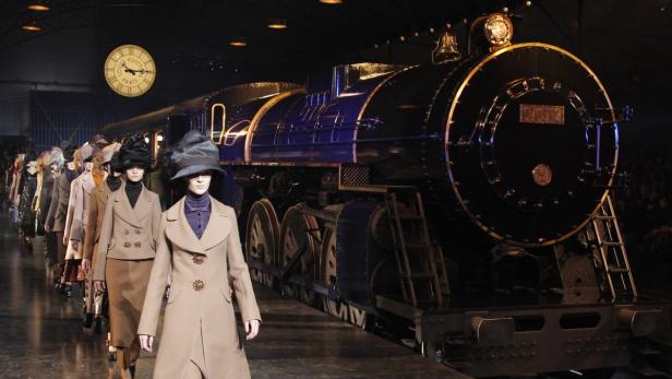 Models präsentieren Mode vor einer großen, dunklen Lokomotive.