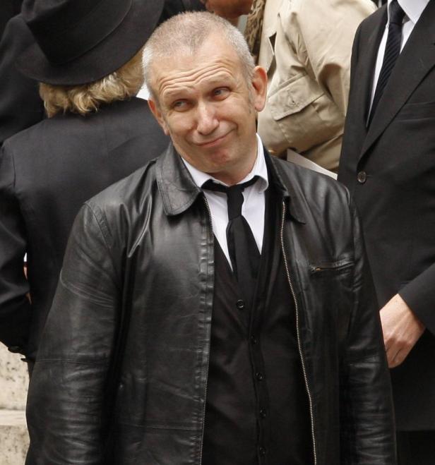 Ein Mann mit schwarzer Lederjacke und Krawatte blickt verschmitzt in die Kamera.