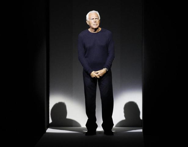 Giorgio Armani steht auf einer Bühne im Rampenlicht.