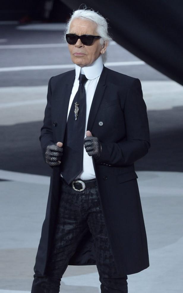 Karl Lagerfeld in dunklem Anzug, Hemd mit hohem Kragen und Sonnenbrille.