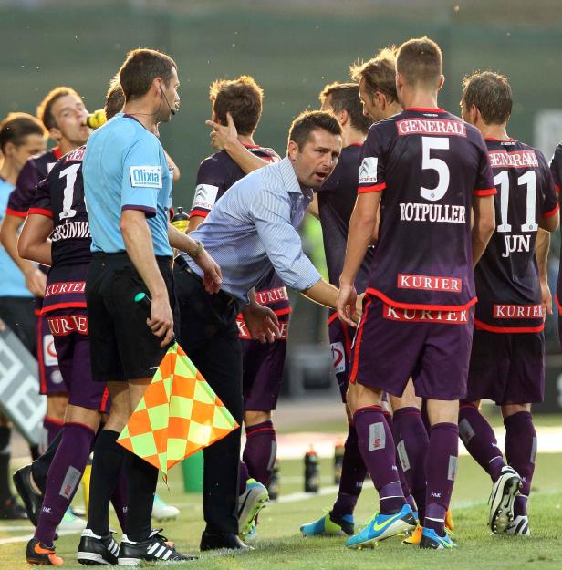 Ein Fußballtrainer begrüßt seine Mannschaft am Spielfeldrand.