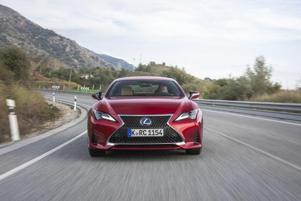 Ein roter Lexus RC fährt auf einer kurvenreichen Straße in den Bergen.